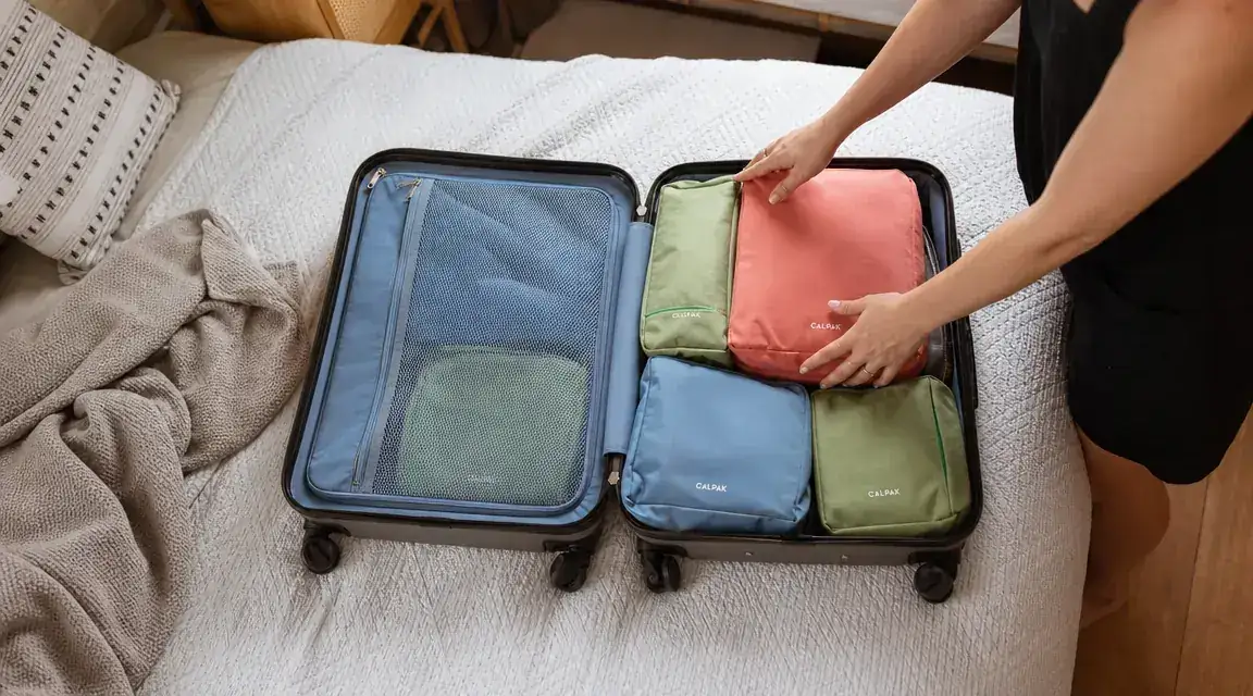 Open suitcase neatly organized with colorful packing cubes on a bed before a family trip