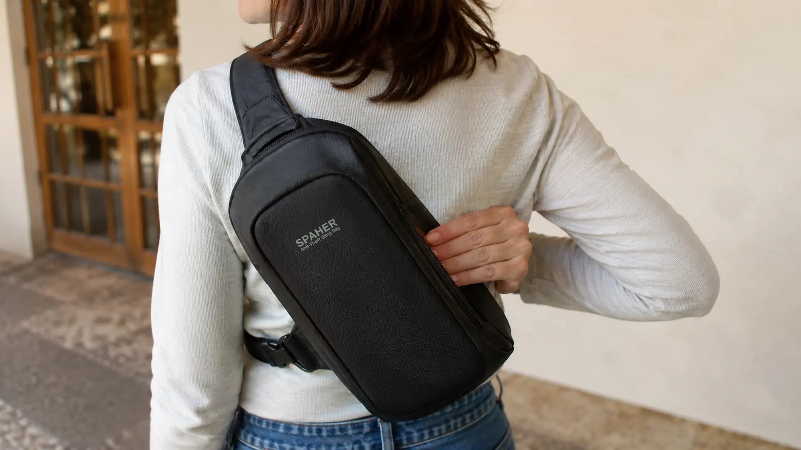 Close-up of a hidden zipper pocket on the back panel of an anti-theft sling bag pressed against a body